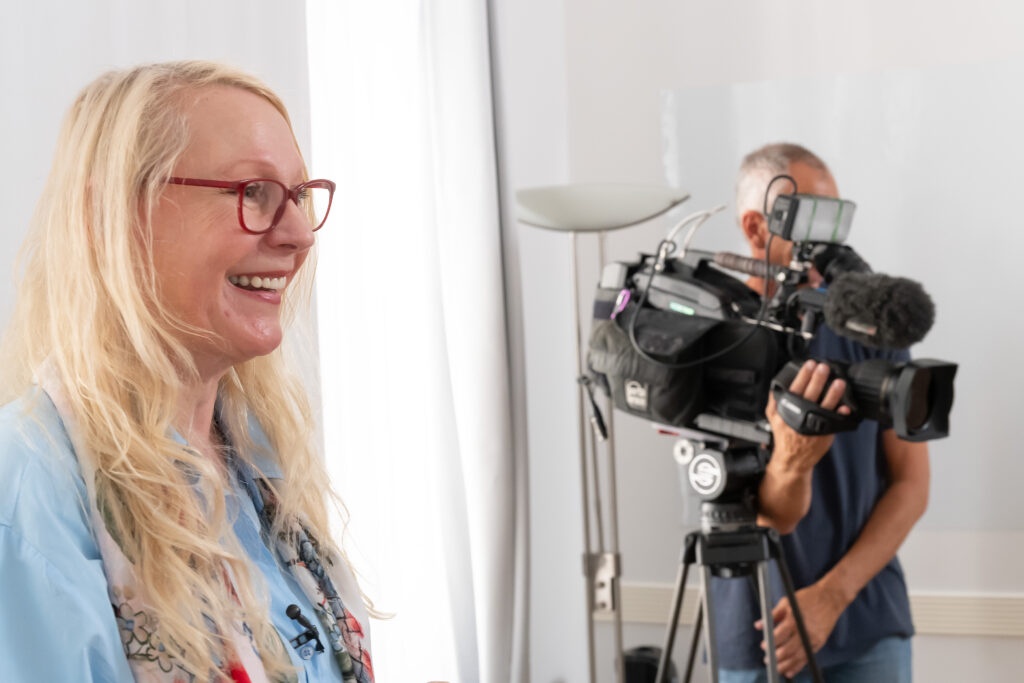 Barbara, lächelnd im Vordergrund. Der Kameraman im Hintergrund.